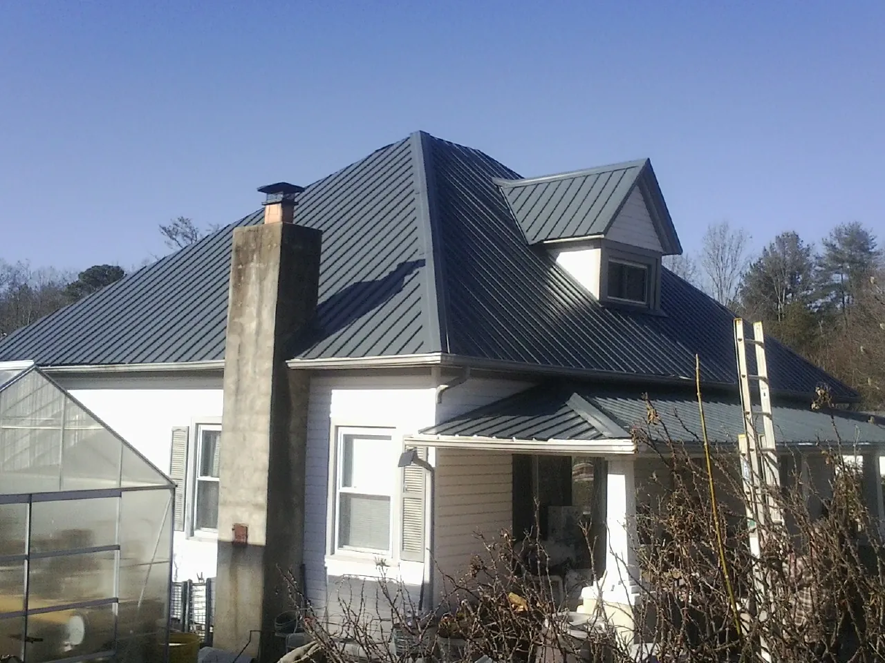 Dark blue standing seam metal roof on a white farmhouse with dormer — Slate & Tile Roof Repair by Roofing Brothers in Weyauwega