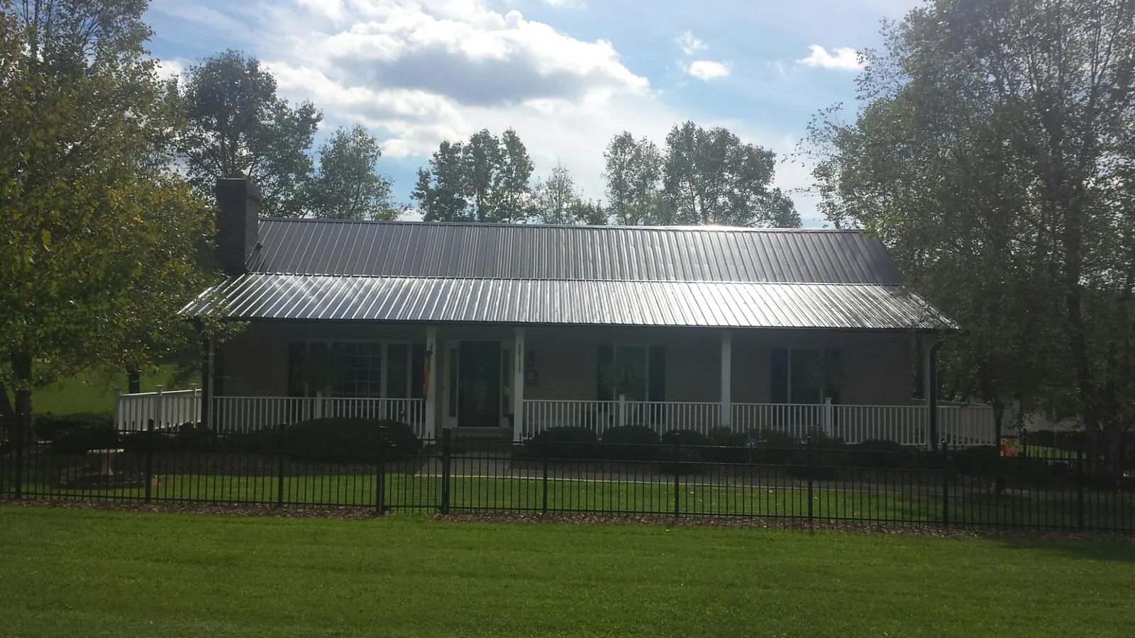 Gray metal roof on a brick ranch with a full width front porch — Gutter Guard Installation work by our crew in Weyauwega
