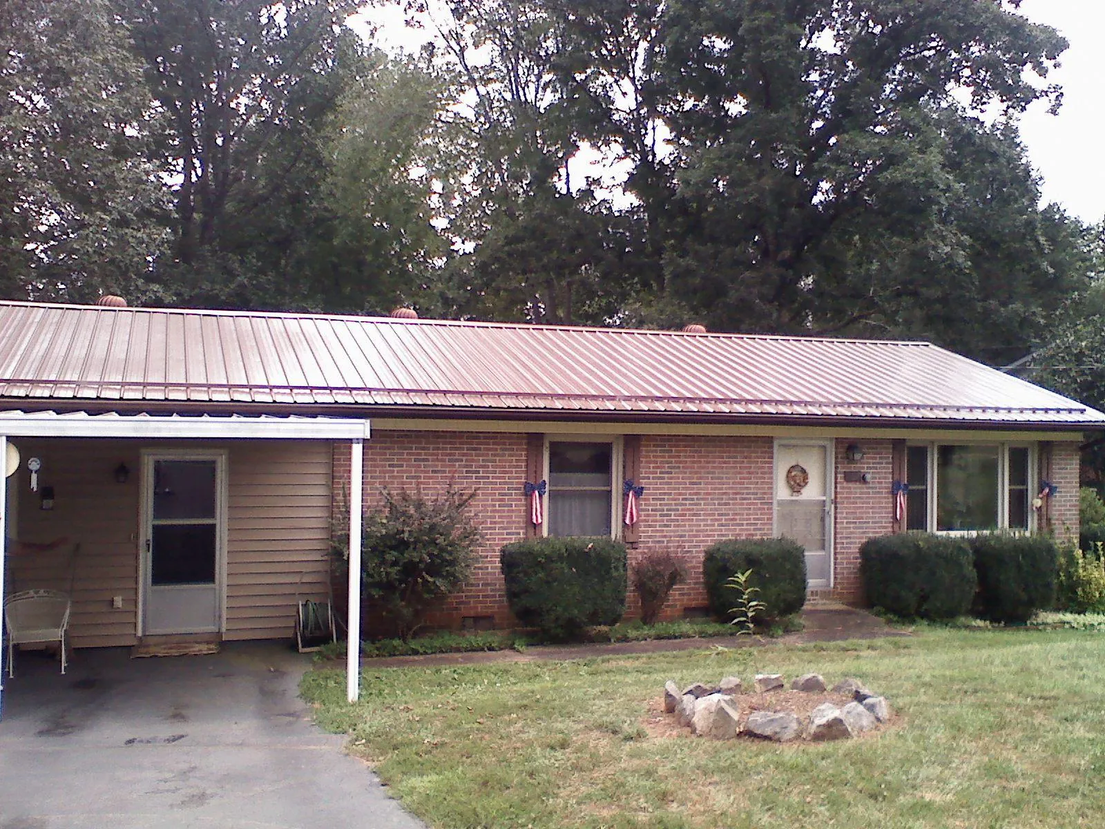 Bronze metal roof and carport on a brick ranch home — Roof Repair work by our crew in Weyauwega