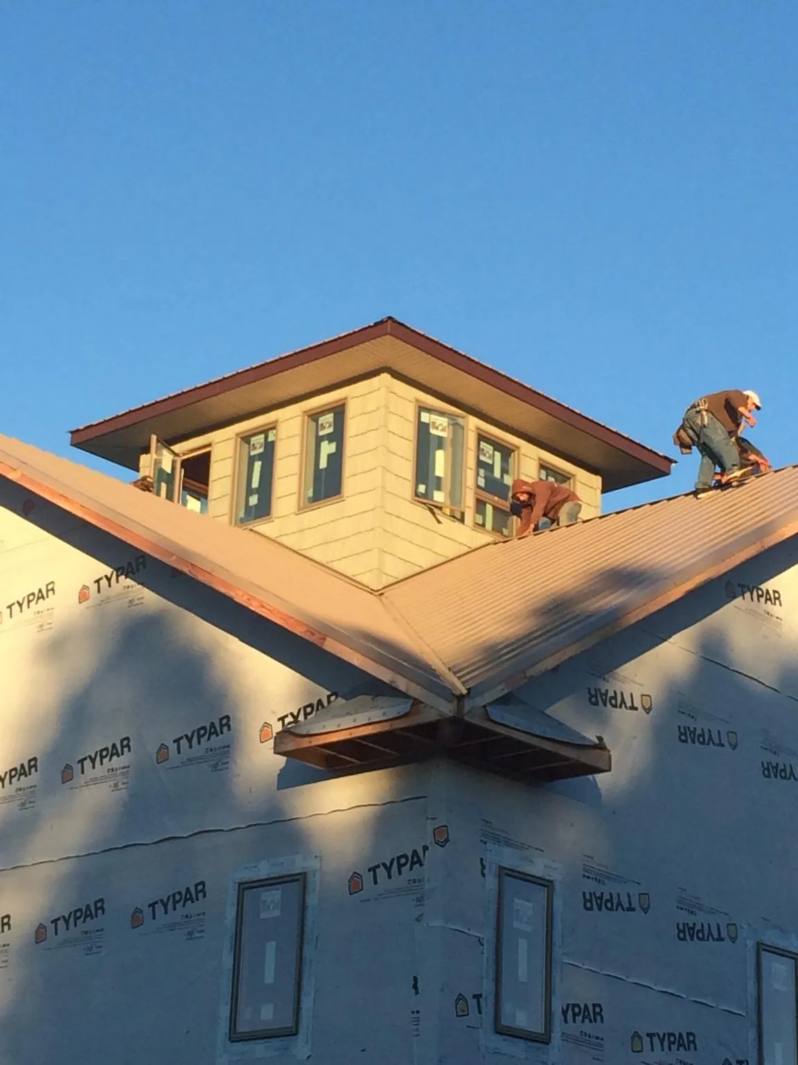 Roofers working around a rooftop cupola on a new metal roof at sunset — Roof Waterproofing in Weyauwega by Roofing Brothers